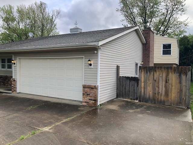 view of side of property featuring a chimney, brick siding, a garage, and fence