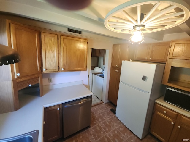 kitchen with independent washer and dryer, freestanding refrigerator, visible vents, light countertops, and stainless steel dishwasher