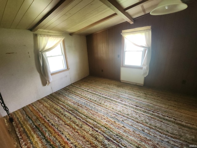 additional living space featuring beamed ceiling, wooden walls, a healthy amount of sunlight, and wood ceiling