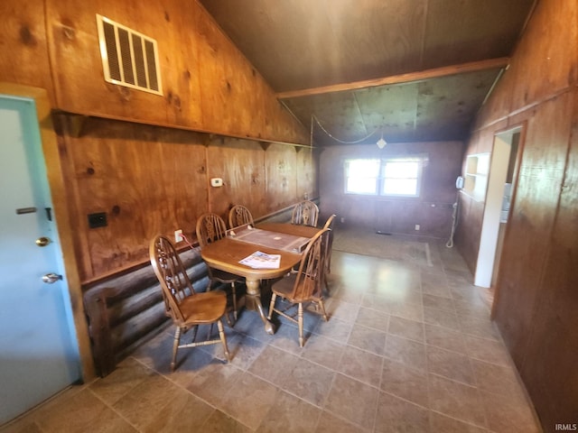 dining room featuring lofted ceiling, wood walls, and visible vents