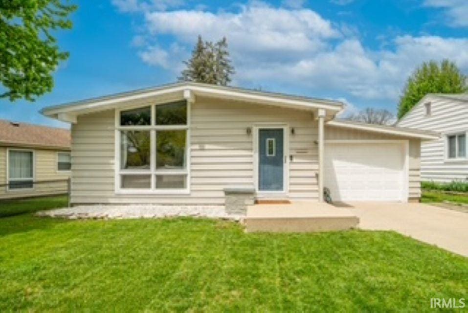 view of front of property featuring a front yard, a garage, and driveway