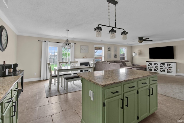 kitchen with light tile patterned floors, a center island, a ceiling fan, crown molding, and green cabinets