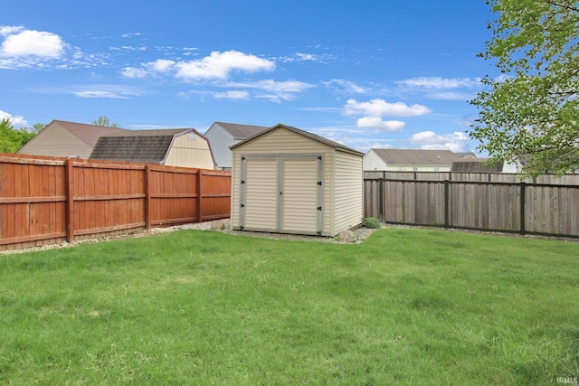 view of yard featuring a fenced backyard, a shed, and an outbuilding