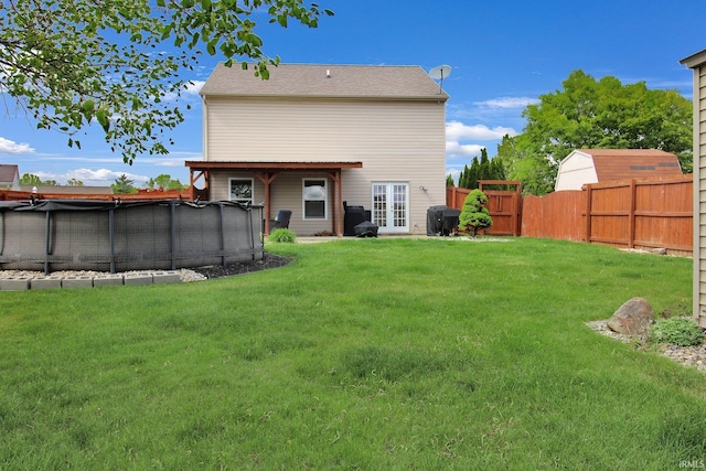 back of house featuring a lawn, a fenced in pool, and fence