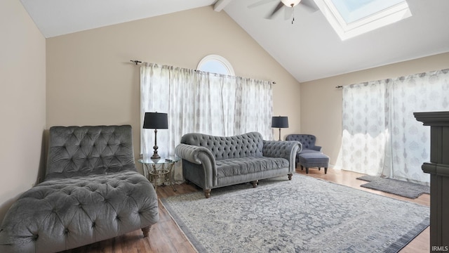 living room featuring wood finished floors, high vaulted ceiling, a skylight, ceiling fan, and beamed ceiling