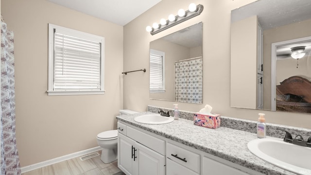full bath featuring double vanity, toilet, baseboards, and a sink