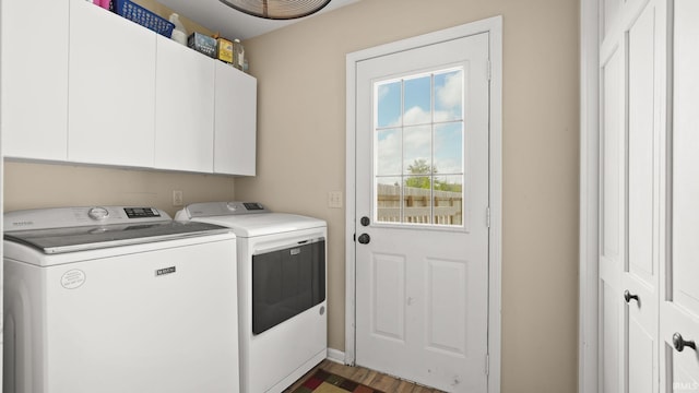 clothes washing area with washing machine and clothes dryer, cabinet space, and wood finished floors