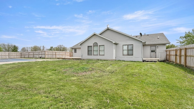 rear view of house with a shingled roof, a lawn, and a fenced backyard
