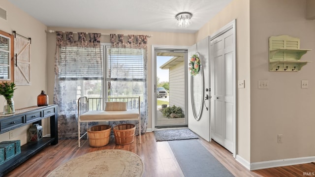 foyer featuring a barn door, visible vents, wood finished floors, and baseboards