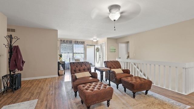sitting room with baseboards, ceiling fan, visible vents, and wood finished floors