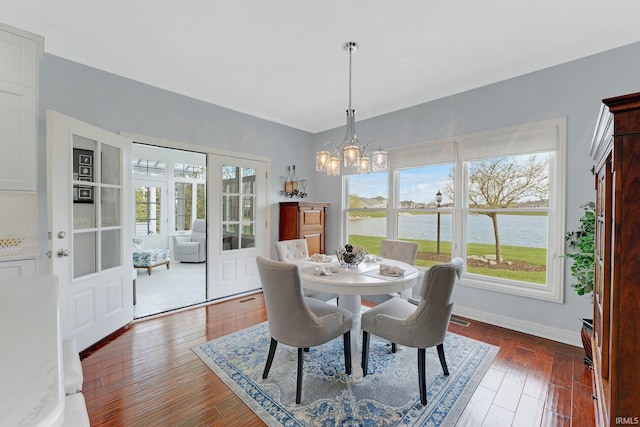 14352 Brolio Dr, Fort Wayne, IN 46814 - dining room with a water view, a chandelier, dark wood-style flooring, and baseboards