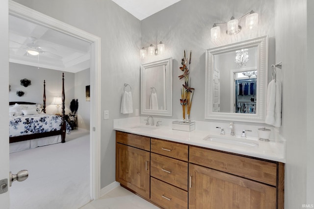 full bath with double vanity, connected bathroom, ceiling fan with notable chandelier, and a sink