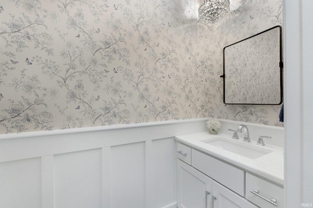 bathroom with vanity, a wainscoted wall, and wallpapered walls
