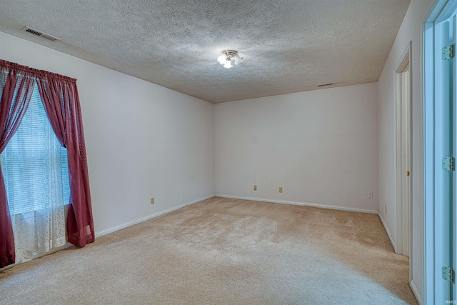 empty room featuring a textured ceiling, baseboards, visible vents, and light colored carpet