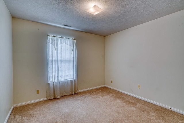 carpeted spare room with baseboards, visible vents, and a textured ceiling