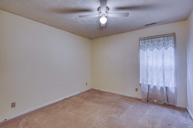 carpeted empty room with a textured ceiling, baseboards, a ceiling fan, and visible vents