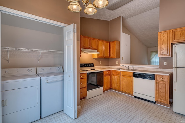 kitchen featuring independent washer and dryer, under cabinet range hood, white appliances, a sink, and vaulted ceiling