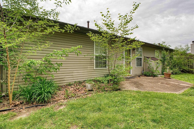 view of property exterior featuring a lawn and a patio area