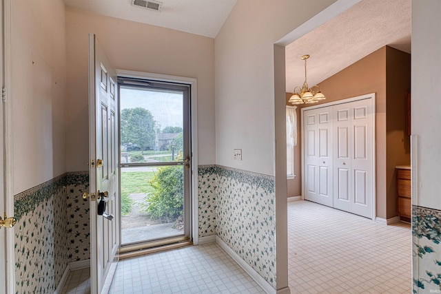 foyer entrance with baseboards, a notable chandelier, visible vents, and a wainscoted wall