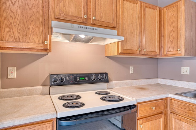 kitchen with light countertops, under cabinet range hood, and electric range