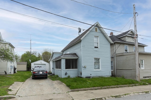 view of front facade with an outdoor structure, a garage, a shingled roof, concrete driveway, and a front yard