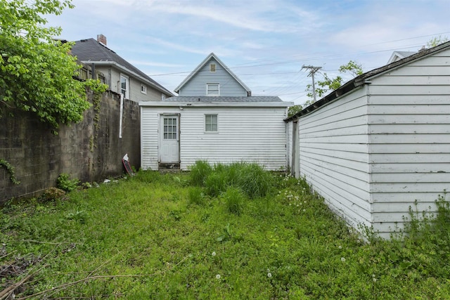 rear view of house with fence and an outdoor structure