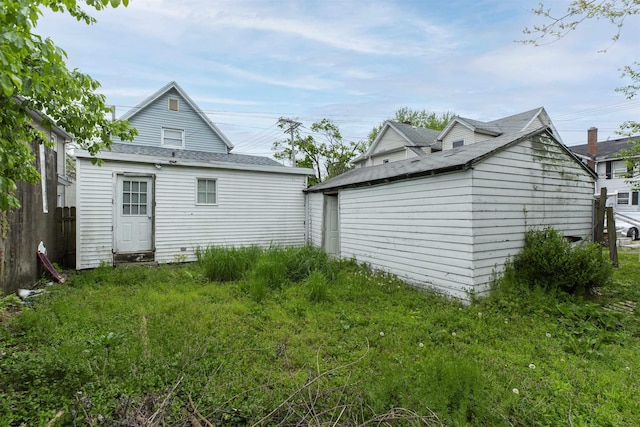 rear view of property with an outbuilding and fence