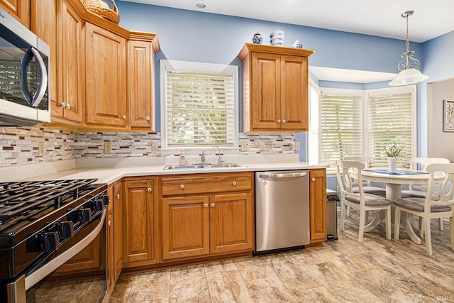 kitchen featuring brown cabinetry, a sink, decorative backsplash, light countertops, and appliances with stainless steel finishes