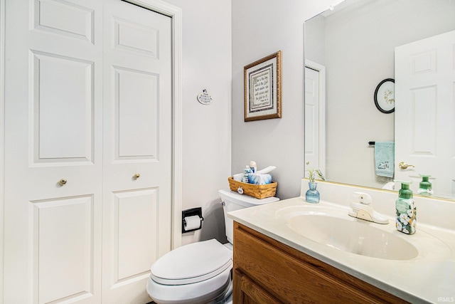 bathroom with a closet, toilet, and vanity