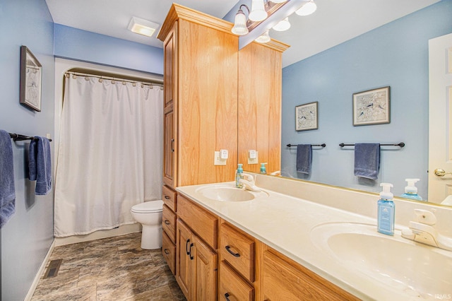 bathroom with a sink, toilet, visible vents, double vanity, and baseboards