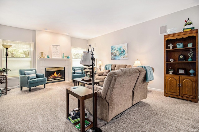 living area with light carpet, baseboards, visible vents, and a glass covered fireplace