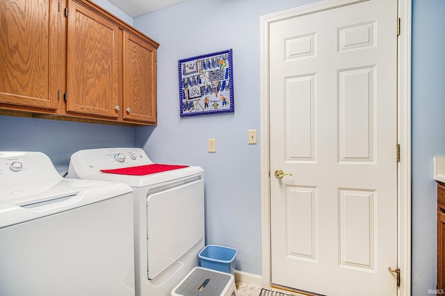 laundry area featuring washing machine and clothes dryer, baseboards, and cabinet space