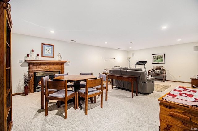 dining area featuring baseboards, a lit fireplace, recessed lighting, and light colored carpet
