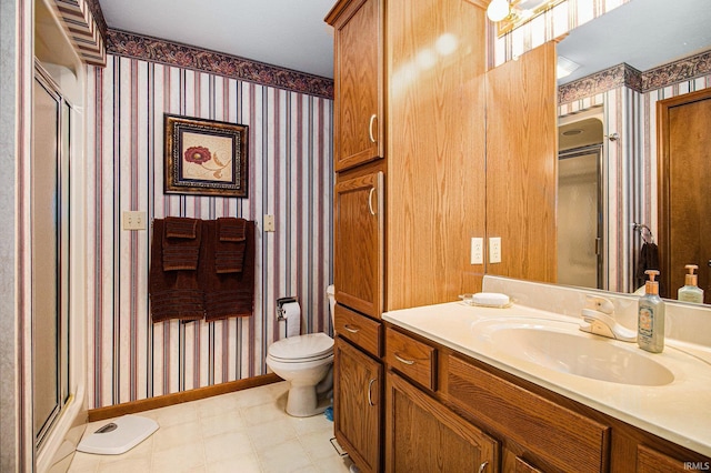 bathroom featuring toilet, wallpapered walls, tile patterned floors, a shower stall, and vanity