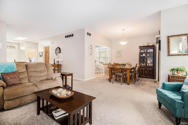 living room with baseboards, visible vents, and light colored carpet
