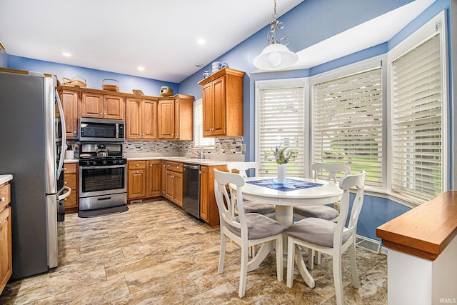 kitchen with light countertops, appliances with stainless steel finishes, plenty of natural light, and backsplash