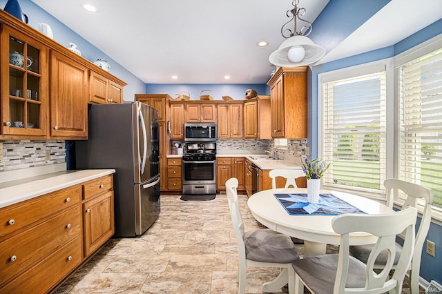 kitchen with brown cabinetry, decorative backsplash, light countertops, and appliances with stainless steel finishes