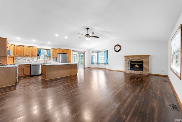 104 S Line St, South Whitley, IN 46787 - unfurnished living room featuring dark wood-type flooring, visible vents, vaulted ceiling, a fireplace, and a ceiling fan