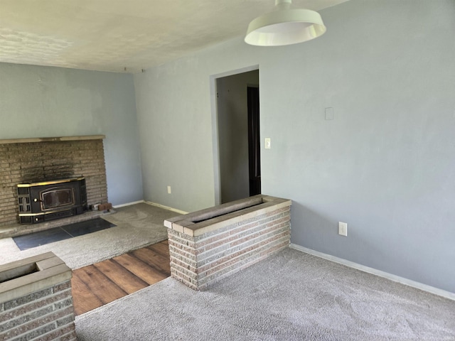 unfurnished living room with a wood stove, baseboards, and carpet floors