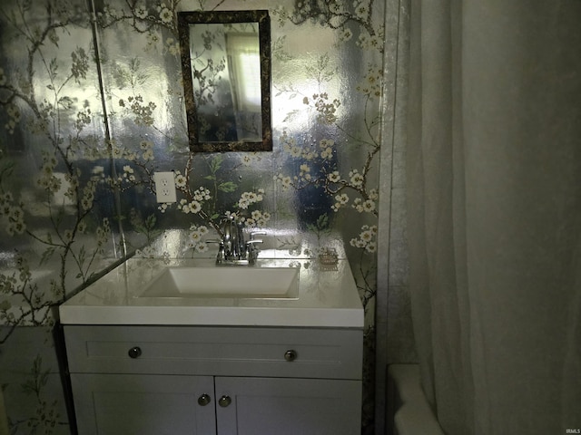 bathroom with wallpapered walls, shower / tub combo with curtain, and vanity