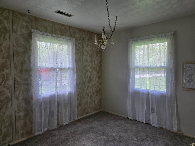 spare room featuring carpet, plenty of natural light, visible vents, and a notable chandelier