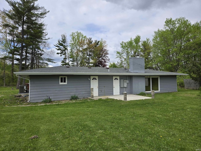 rear view of house featuring a yard, a patio area, a chimney, and central AC