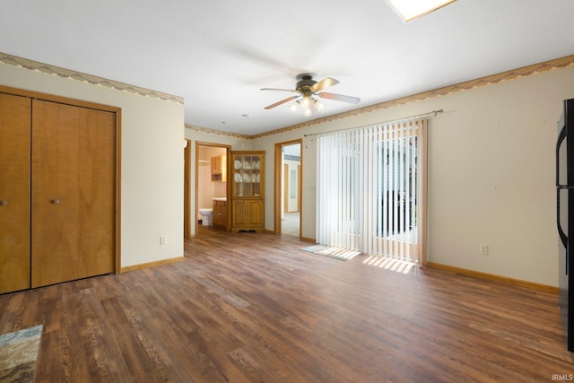 unfurnished bedroom with wood finished floors, freestanding refrigerator, a closet, ensuite bathroom, and baseboards