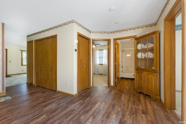 spare room with baseboards and dark wood-type flooring