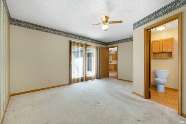 unfurnished bedroom with light colored carpet, a textured ceiling, and baseboards