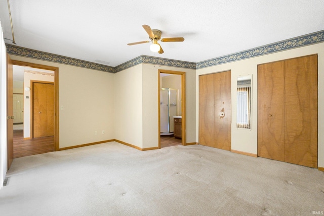 unfurnished bedroom featuring ensuite bath, baseboards, multiple closets, and carpet floors