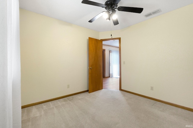 unfurnished room featuring light colored carpet, visible vents, baseboards, and a ceiling fan