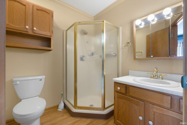 bathroom with toilet, wood finished floors, a shower stall, vanity, and ornamental molding