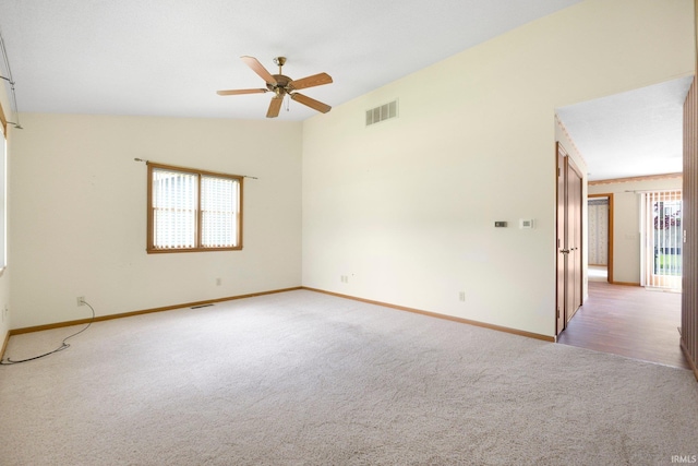 spare room with lofted ceiling, visible vents, light carpet, a ceiling fan, and baseboards