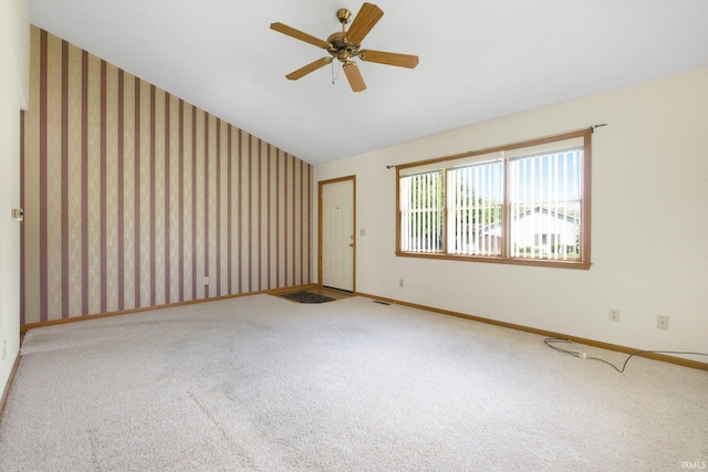 carpeted spare room with wallpapered walls, vaulted ceiling, baseboards, and visible vents